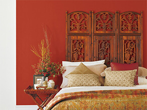 Red oriental bedroom with wooden bedhead and bamboo bedside table with gold throw blanket and pillow